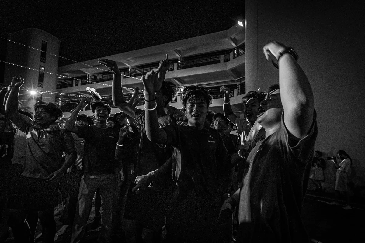 A crowd cheering and raising their hands at a night event
