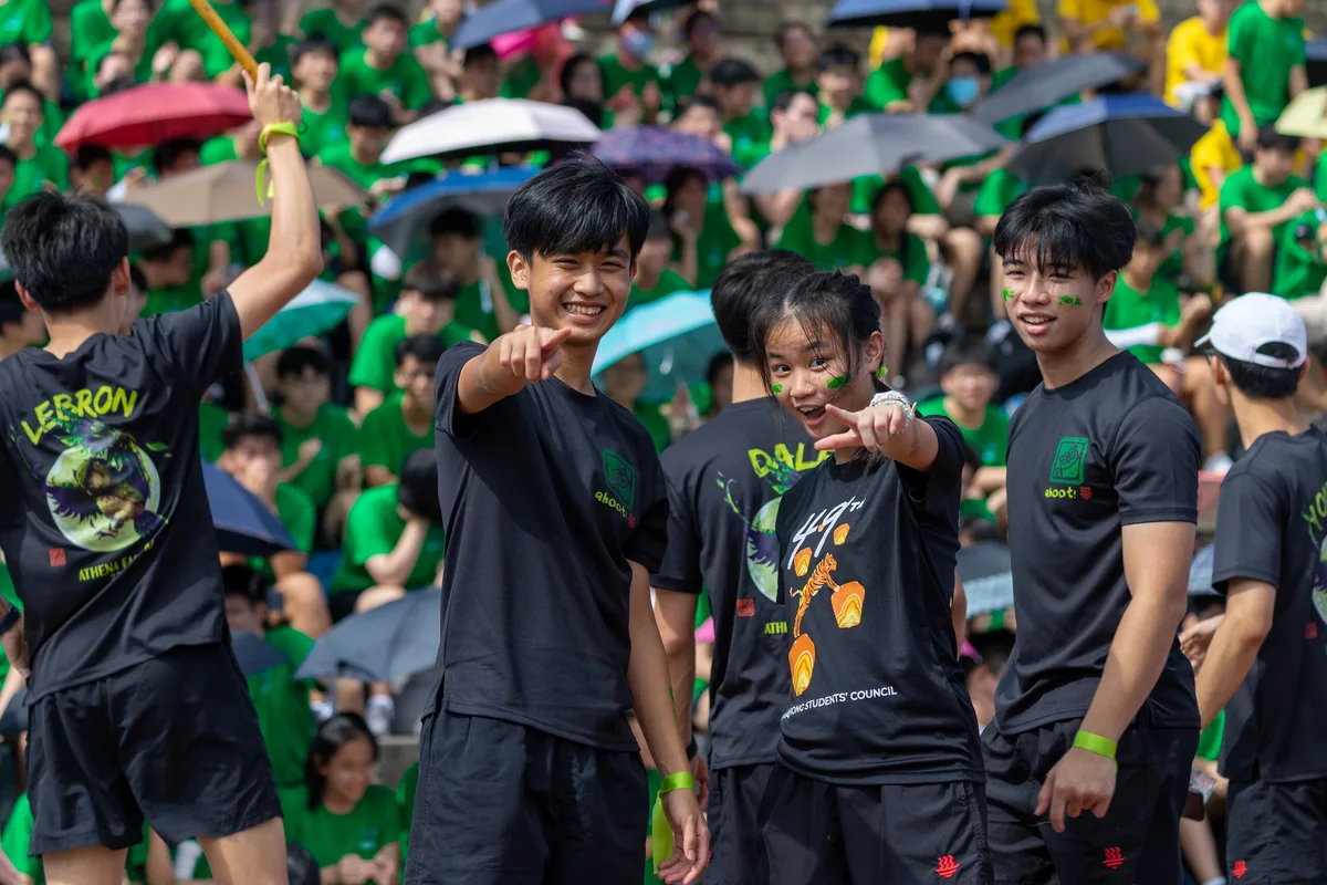 Members of a university team in green smiling together in a crowd