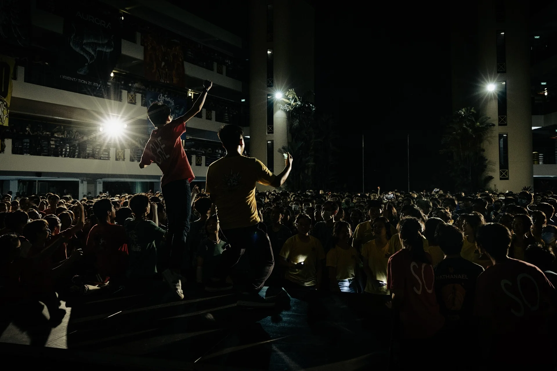 A performer silhouetted by a bright stage light in front of an audience
