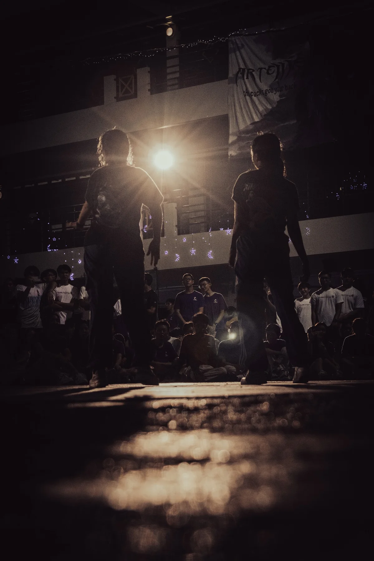 Two performers standing in a beam of light at a night event