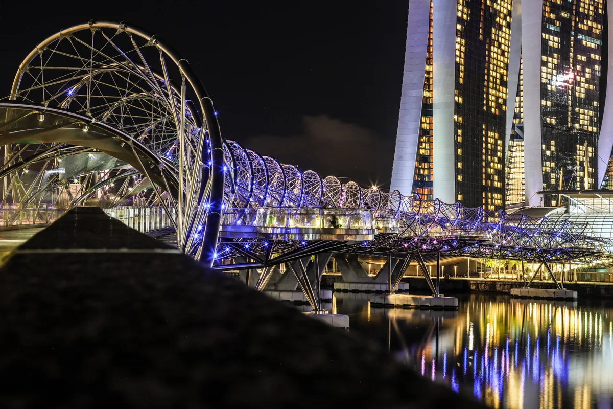 The illuminated Helix Bridge and city skyline at night